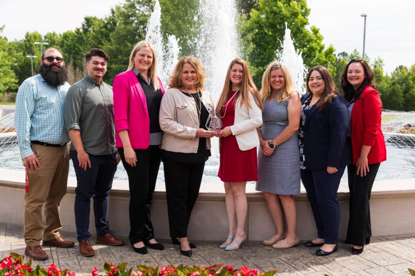 Team photo holding award in front of fountain