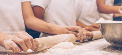 Rolling pin rolling out dough on cutting board