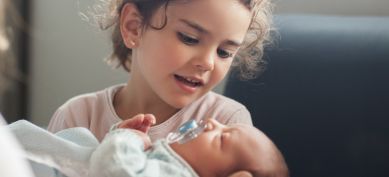 Young child holding newborn baby