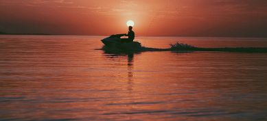 Personal watercraft on lake at sunset