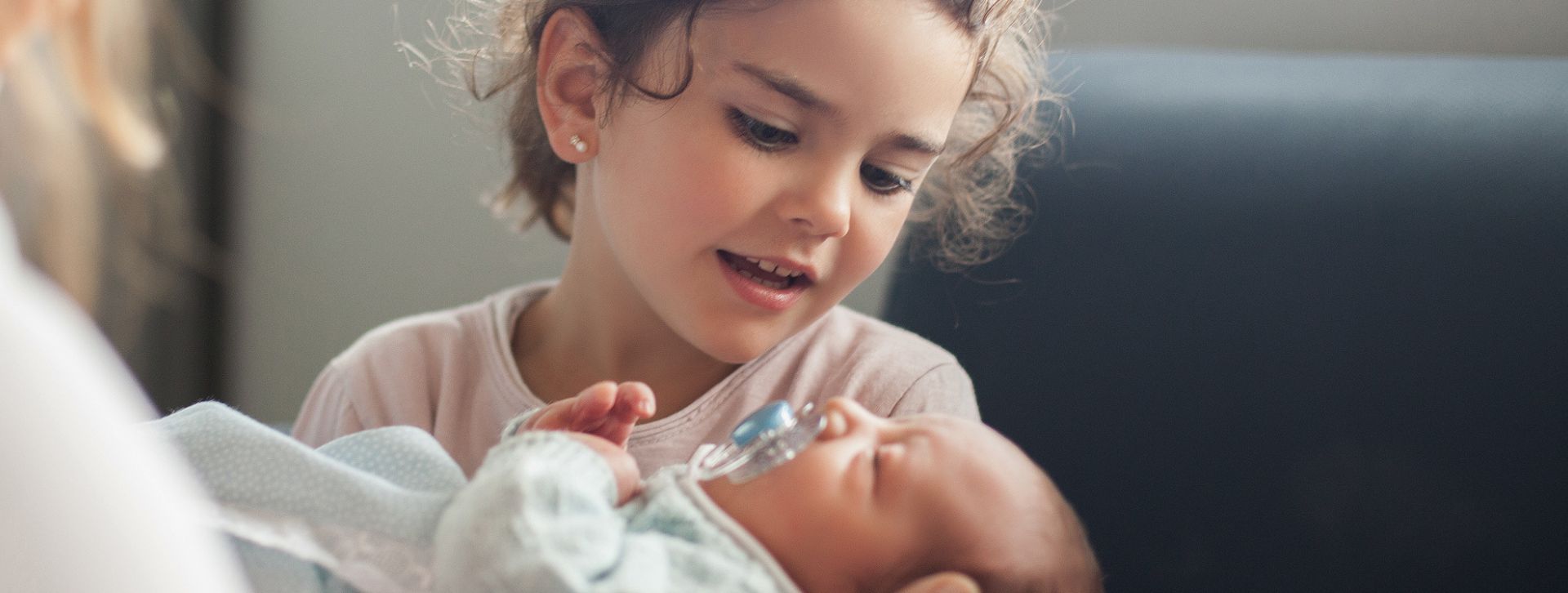 Young child holding newborn baby